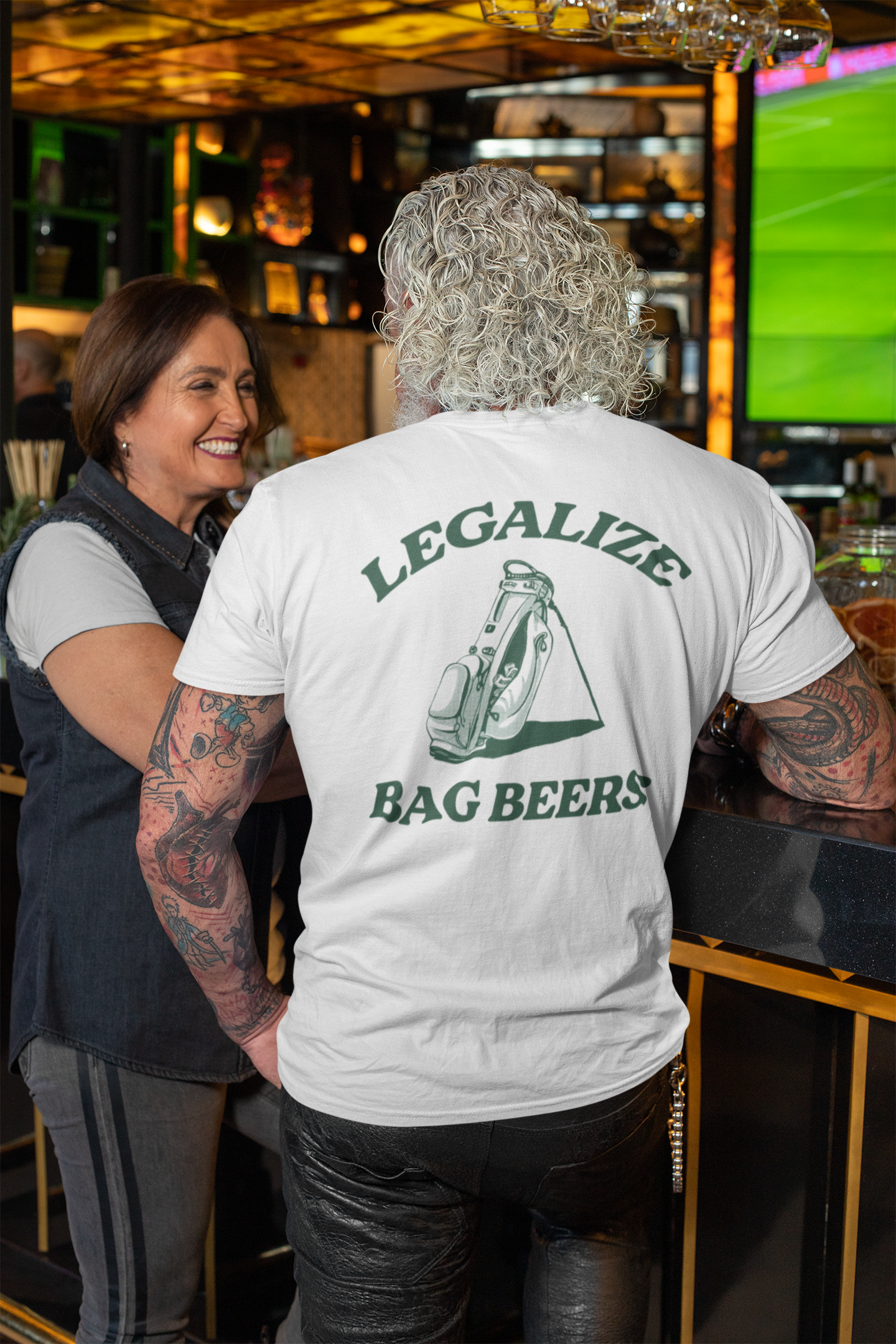 Person wearing a t-shirt with 'Legalize Bag Beers' text in a bar setting